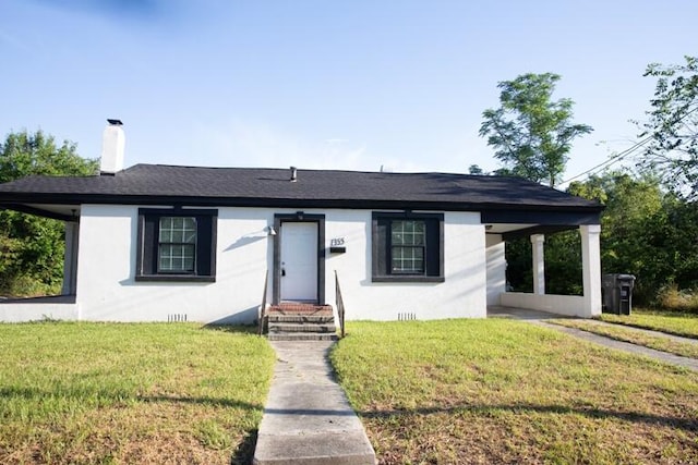 view of front of property with a chimney, a front yard, and stucco siding