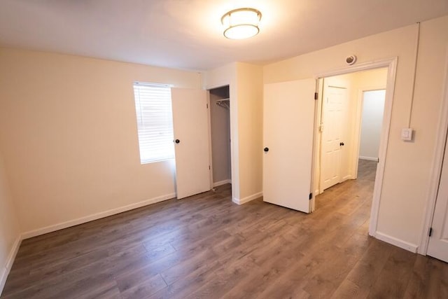 unfurnished bedroom with a closet, wood finished floors, and baseboards