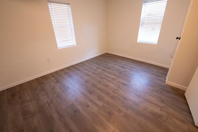 spare room featuring baseboards and dark wood-style floors