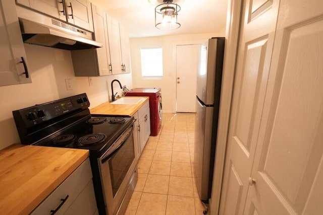 kitchen featuring washer and dryer, butcher block countertops, appliances with stainless steel finishes, and under cabinet range hood