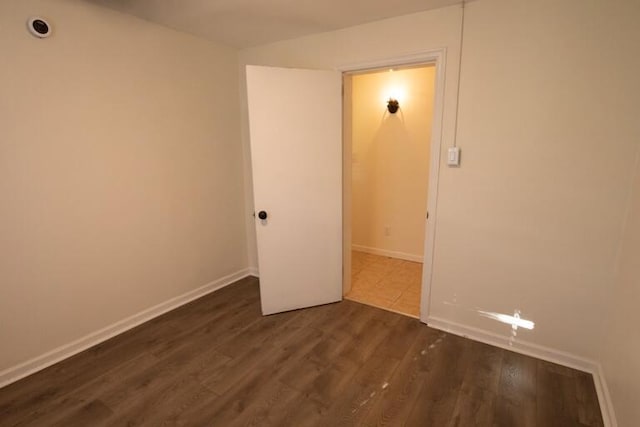 unfurnished room featuring baseboards and dark wood finished floors