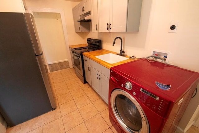 washroom with a sink, laundry area, light tile patterned floors, and washer / dryer