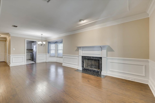 unfurnished living room with visible vents, ornamental molding, dark wood-style flooring, a fireplace, and a notable chandelier