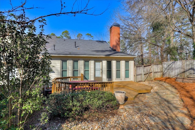 rear view of house featuring a chimney, fence, and a wooden deck