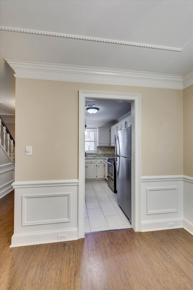 kitchen featuring appliances with stainless steel finishes, light wood-type flooring, and crown molding