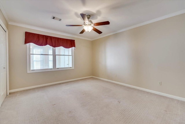 spare room featuring carpet floors, baseboards, visible vents, and crown molding