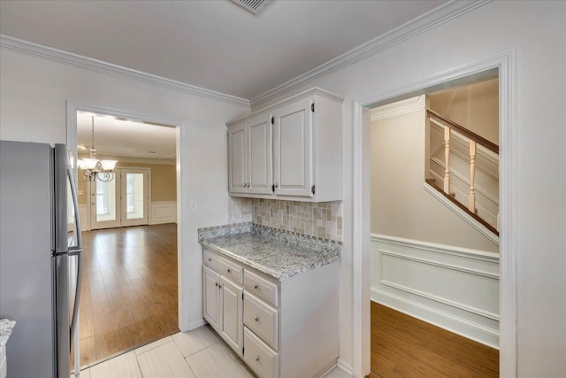 kitchen with light wood-style floors, wainscoting, freestanding refrigerator, and crown molding