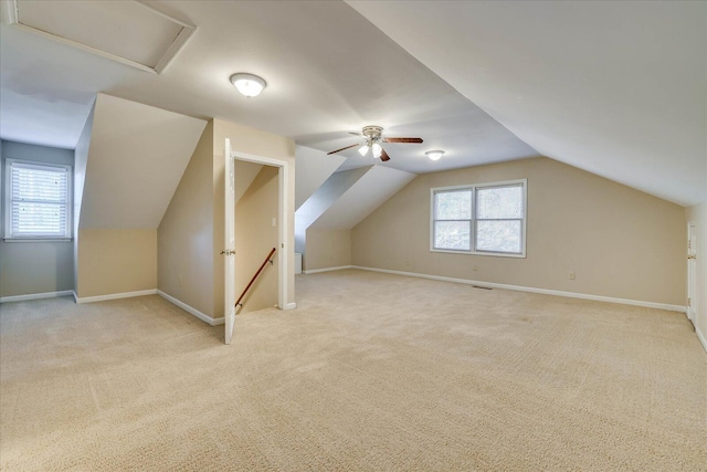 additional living space with baseboards, plenty of natural light, attic access, and light colored carpet