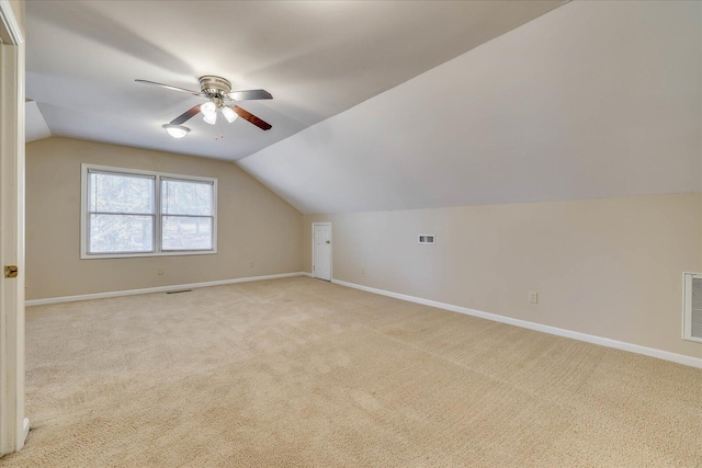 additional living space with baseboards, vaulted ceiling, visible vents, and light colored carpet