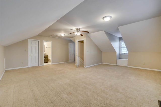 additional living space featuring baseboards and light colored carpet