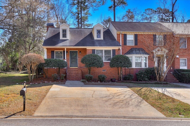 view of front of home featuring brick siding, a chimney, and a front lawn