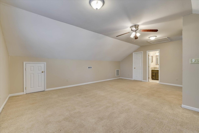 additional living space with attic access, baseboards, visible vents, light colored carpet, and vaulted ceiling