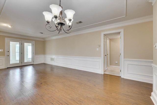 empty room featuring wood finished floors, visible vents, and a notable chandelier