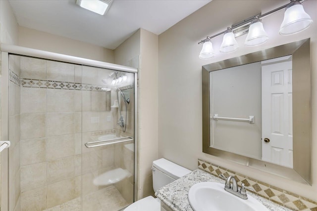 full bathroom featuring a stall shower, vanity, and toilet