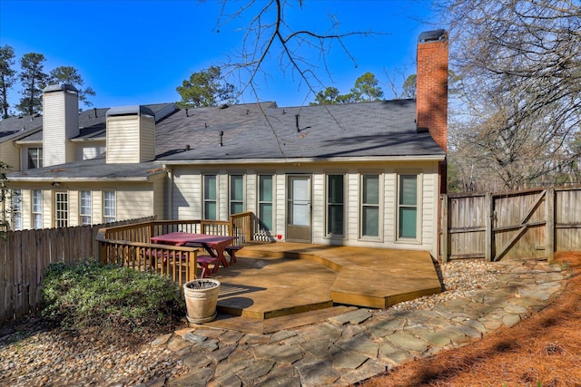 rear view of property with a gate, a chimney, fence, and a wooden deck