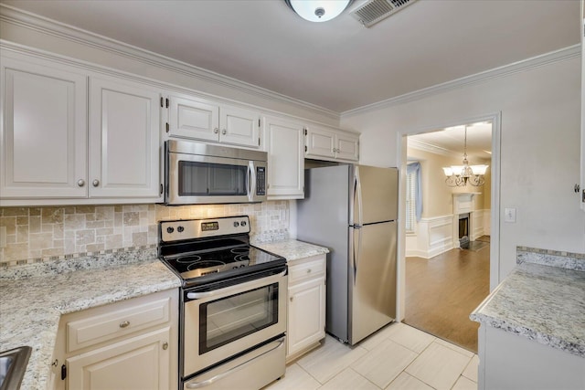 kitchen featuring a wainscoted wall, stainless steel appliances, visible vents, decorative backsplash, and crown molding