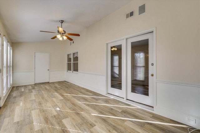 empty room featuring french doors, a wainscoted wall, visible vents, ceiling fan, and light wood-type flooring