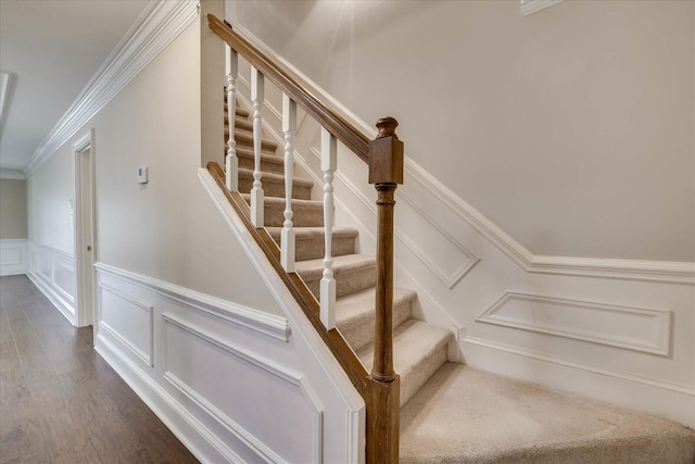 staircase featuring ornamental molding, wainscoting, a decorative wall, and wood finished floors