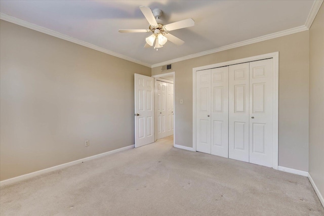 unfurnished bedroom featuring carpet floors, a closet, visible vents, ornamental molding, and baseboards