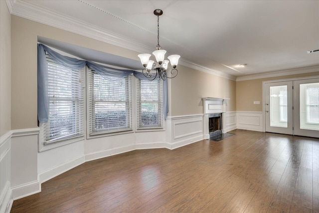 unfurnished living room featuring ornamental molding, dark wood-type flooring, an inviting chandelier, and a healthy amount of sunlight