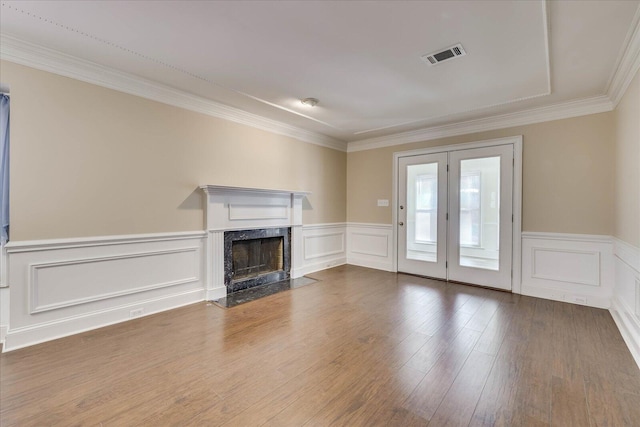 unfurnished living room featuring wainscoting, visible vents, a fireplace, and wood finished floors