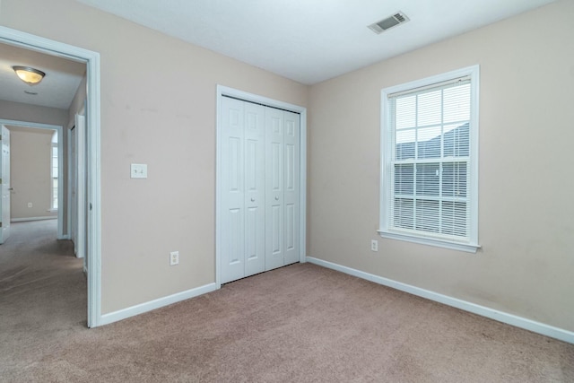 unfurnished bedroom with light carpet and a closet