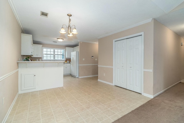 kitchen featuring an inviting chandelier, white cabinets, crown molding, white fridge, and kitchen peninsula