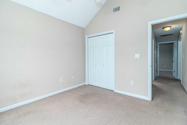 unfurnished bedroom featuring light colored carpet, lofted ceiling, and a closet