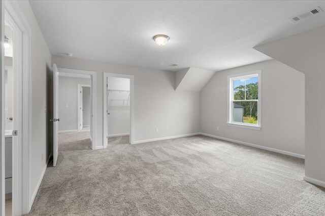 additional living space featuring vaulted ceiling and light carpet