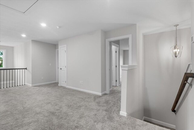 empty room featuring light carpet and a chandelier