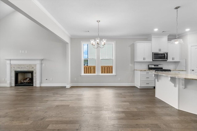 kitchen featuring light stone countertops, appliances with stainless steel finishes, pendant lighting, and white cabinets