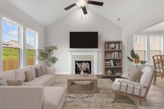 living room with vaulted ceiling, ceiling fan, a fireplace, and light hardwood / wood-style flooring