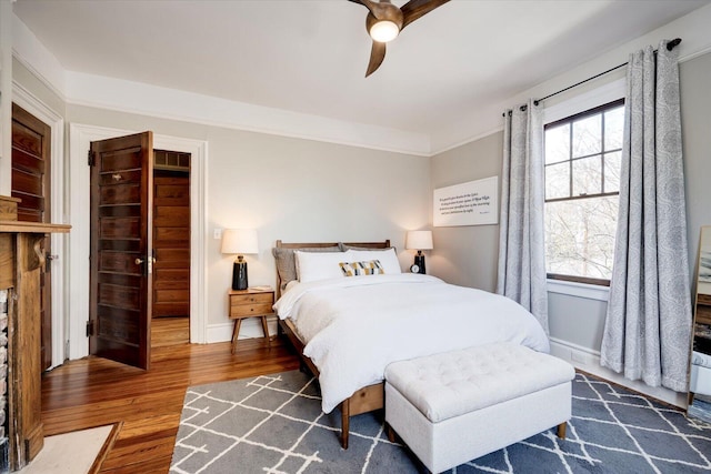 bedroom featuring baseboards, wood finished floors, and a ceiling fan