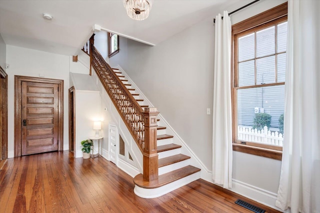 stairs with visible vents, plenty of natural light, baseboards, and hardwood / wood-style flooring