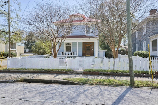 american foursquare style home featuring a fenced front yard and covered porch