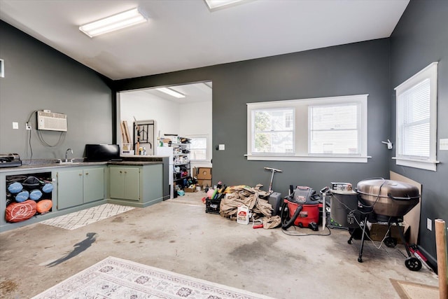 misc room featuring an AC wall unit, unfinished concrete flooring, and a sink