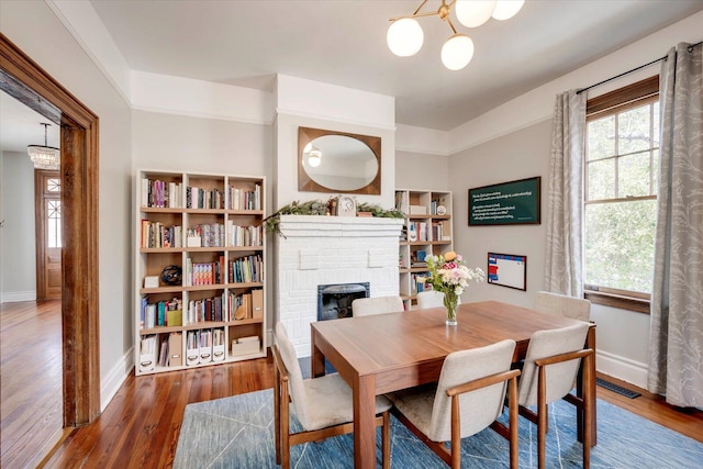 dining space with a wealth of natural light, visible vents, a brick fireplace, and wood finished floors