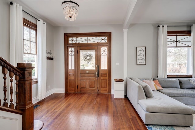 foyer with a wealth of natural light, a notable chandelier, baseboards, and wood-type flooring