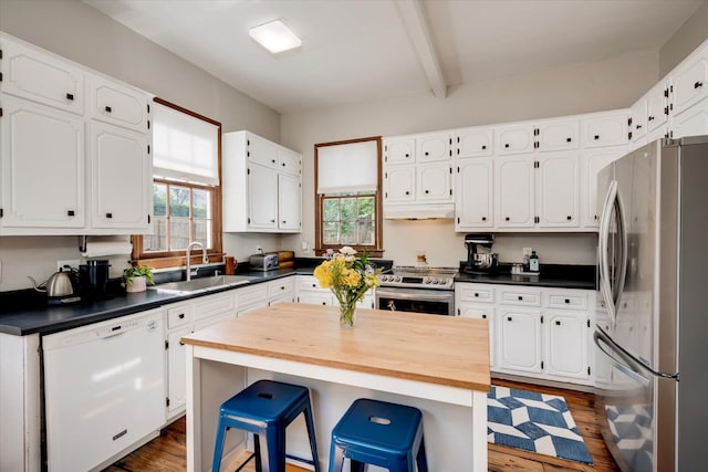 kitchen with a sink, a wealth of natural light, appliances with stainless steel finishes, and white cabinets