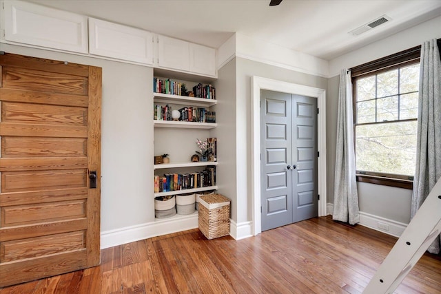 interior space featuring visible vents, baseboards, and wood finished floors