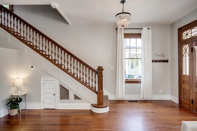 foyer featuring visible vents, baseboards, a chandelier, stairway, and wood finished floors