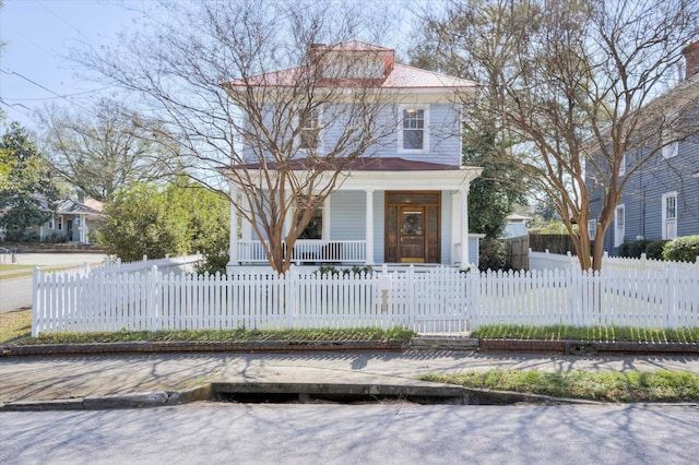 american foursquare style home with a fenced front yard and covered porch