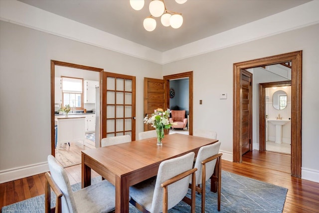 dining space with baseboards, an inviting chandelier, and hardwood / wood-style flooring