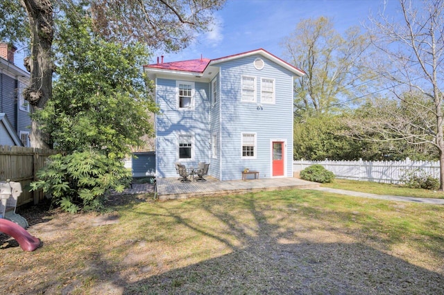 rear view of property with a fenced backyard and a yard