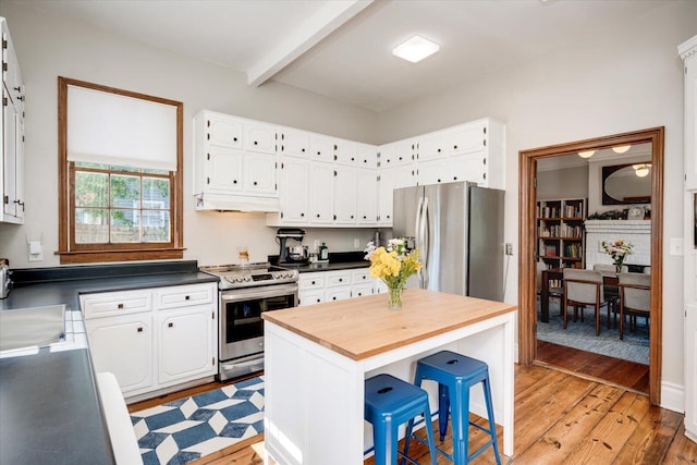 kitchen with white cabinets, beamed ceiling, light wood finished floors, and stainless steel appliances