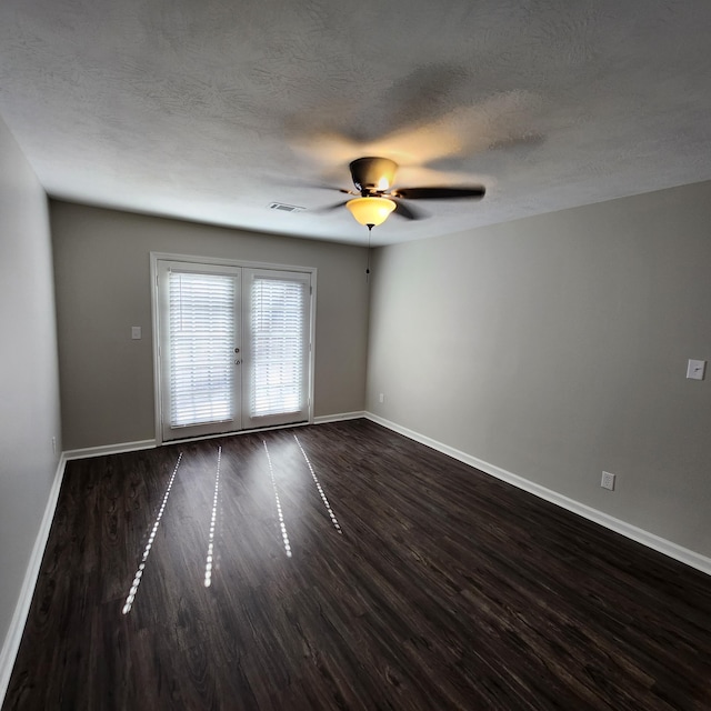 empty room with visible vents, baseboards, ceiling fan, dark wood-type flooring, and a textured ceiling