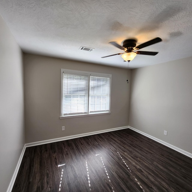 empty room with baseboards, ceiling fan, dark wood-type flooring, and visible vents