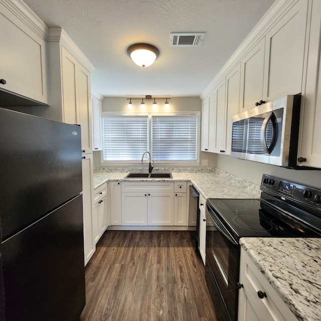 kitchen featuring visible vents, dark wood finished floors, a sink, black appliances, and white cabinetry