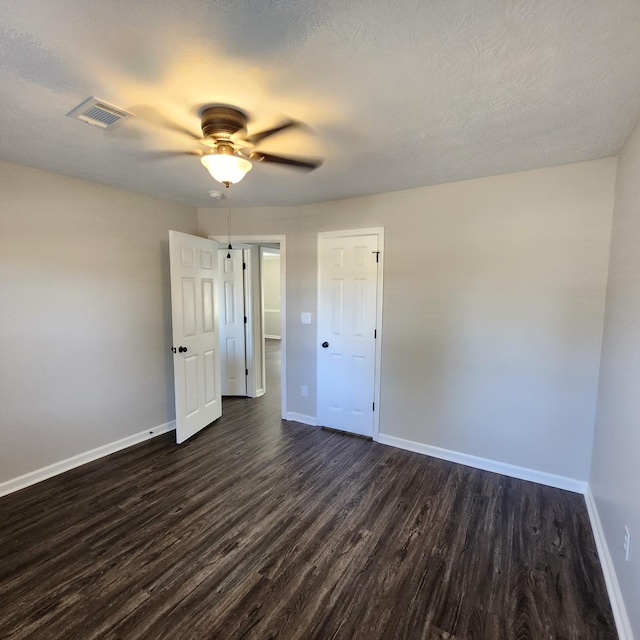 unfurnished bedroom featuring baseboards, ceiling fan, dark wood-style flooring, and visible vents