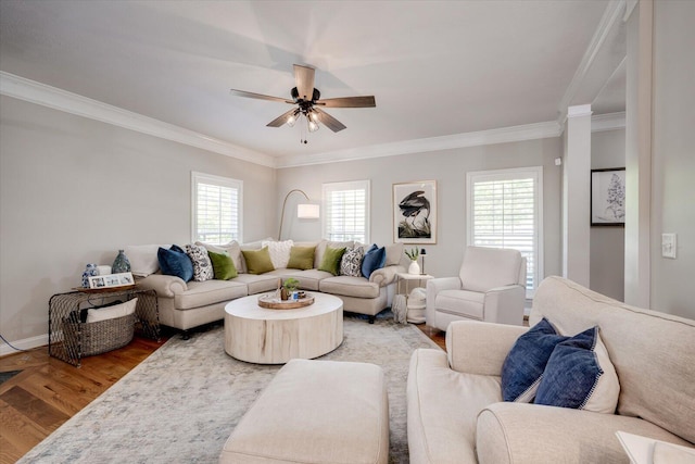 living area featuring baseboards, ornamental molding, a ceiling fan, and wood finished floors